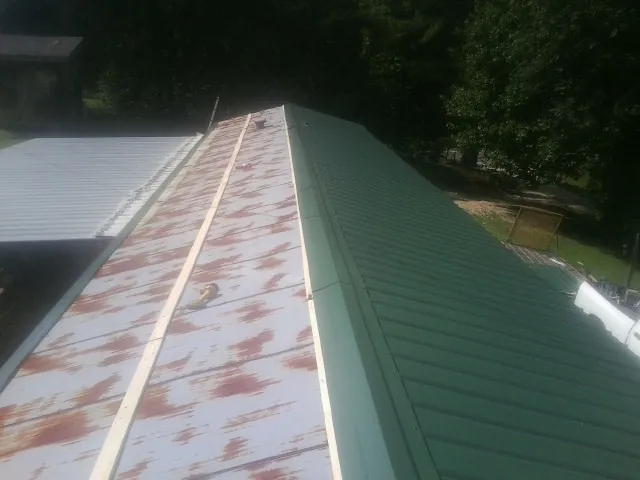 Old rusted panels beside newly installed green metal roofing — Wind Damage Roof Repair by Roofing Brothers in Addison